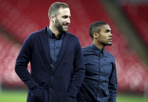 Juventus Gonzalo Higuain, left),and Douglas Costa on the pitch before the press conference at Wembley Stadium, London, Tuesday March 6, 2018. Juventus face Tottenham Hotspur in a Champions League soccer, round of 16, 2nd leg match in London on Wednesday. (Steven Paston/PA via AP)