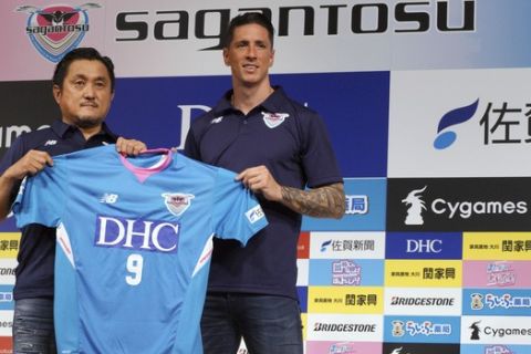 Fernando Torres, right, and Sagan Tosu President Minoru Takehara, left, hold an uniform of Sagan Tosu during a press conference in Tokyo Sunday, July 15, 2018. Former Spain striker Torres signed to play for Sagan Tosu in the J1 League last week. (AP Photo/Eugene Hoshiko)