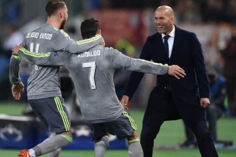 Real Madrid's Portuguese forward Cristiano Ronaldo (C) celebrates with Real Madrid's defender Sergio Ramos and Real Madrid's French coach Zinedine Zidane after scoring during the UEFA Champions League football match AS Roma vs Real Madrid on Frebruary 17, 2016 at the Olympic stadium in Rome.     AFP PHOTO / ALBERTO PIZZOLI / AFP / ALBERTO PIZZOLI        (Photo credit should read ALBERTO PIZZOLI/AFP/Getty Images)