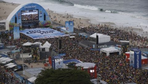 Fans hold up a banner that reads, "Rio loves you, see you soon," as they wait for the live broadcast of the third place soccer match between Brazil and the Netherlands, inside the FIFA Fan Fest area on Copacabana beach, in Rio de Janeiro, Brazil, Saturday, July 12, 2014. (AP Photo/Silvia Izquierdo)