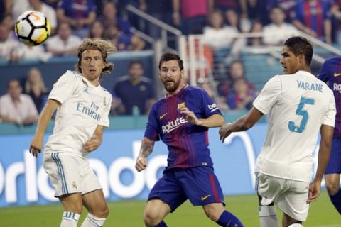 Barcelona's Lionel Messi, center, watches after kicking the ball for a goal as Real Madrid's Luka Modric, left, and Raphael Varane (5) look on during the first half of an International Champions Cup soccer match, Saturday, July 29, 2017, in Miami Gardens, Fla. (AP Photo/Lynne Sladky)