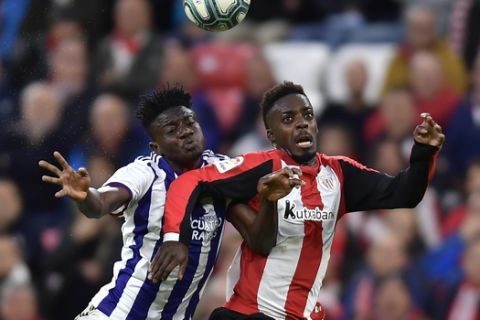 Athletic Bilbao's Inaki Williams, right, jumps for the ball in front Valladolid's Mohammed Salisu before scoring his goal during the Spanish La Liga soccer match between Athletic Bilbao and Valladolid at San Mames stadium in Bilbao, northern Spain, Sunday, Oct. 20, 2019. (AP Photo/Alvaro Barrientos)