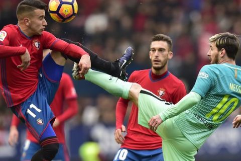 FC Barcelona's Lionel Messi duels for the ball with Osasuna's Alex Berenguer during the Spanish La Liga soccer match between FC Barcelona and Osasuna, at El Sadar stadium, in Pamplona, northern Spain, Saturday, Dec.10, 2016. FC Barcelona won the match 3-0. (AP Photo/Alvaro Barrientos)