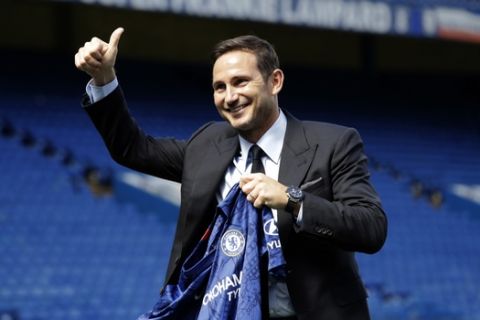 The new Chelsea manager their former player Frank Lampard poses for photographers with a club shirt by the pitch at Stamford Bridge stadium in London, Thursday, July 4, 2019. Lampard has returned to Chelsea as the club's 12th manager in 16 years under Roman Abramovich's ownership. The former Chelsea midfielder has left second-tier club Derby, where he came close to securing promotion to the Premier League in his first season in management. Lampard, who is Chelsea's record scorer with 211 goals and one of its all-time greats, replaces Maurizio Sarri. (AP Photo/Matt Dunham)