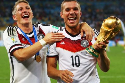 RIO DE JANEIRO, BRAZIL - JULY 13:  Bastian Schweinsteiger and Lukas Podolski of Germany celebrate with the World Cup trophy  after defeating Argentina 1-0 in extra time during the 2014 FIFA World Cup Brazil Final match between Germany and Argentina at Maracana on July 13, 2014 in Rio de Janeiro, Brazil.  (Photo by Julian Finney/Getty Images)