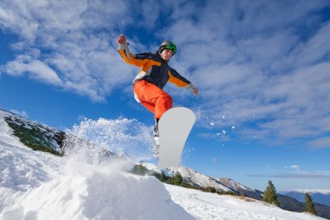 Man jumping with snowboard from mountain hill in winter