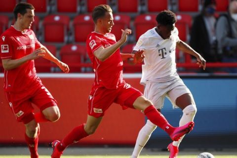 FC Union Berlin's Marcus Ingvartsen in action with Bayern Munich's Alphonso Davies, right, during the German Bundesliga soccer match between Union Berlin and Bayern Munich in Berlin, Germany, Sunday, May 17, 2020. The German Bundesliga becomes the world's first major soccer league to resume after a two-month suspension because of the coronavirus pandemic. (AP Photo/Hannibal Hanschke, Pool)