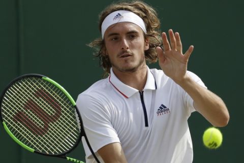 Stefanos Tsitsipas of Greece returns a ball to John Isner of the US during their men's singles match on the seventh day at the Wimbledon Tennis Championships in London, Monday July 9, 2018. (AP Photo/Ben Curtis)