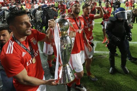 Benfica's Andreas Samaris, left, and team captain Jardel carry the trophy around the stadium close to the fans after the Portuguese league last round soccer match between Benfica and Santa Clara at the Luz stadium in Lisbon, Saturday, May 18, 2019. Benfica won 4-1 to clinch the championship title. (AP Photo/Armando Franca)