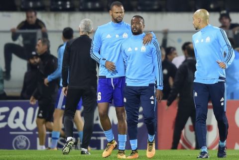 Marseille's Patrice Evra, center right, is led away by his teammate Rolando after a scuffle with Marseille supporters who trespassed into the field before the Europa League group I soccer match between Vitoria SC and Olympique de Marseille at the D. Afonso Henriques stadium in Guimaraes, Portugal, Thursday, Nov. 2, 2017. Evra was shown a red card before the start of the match for his involvement in the incident. (AP Photo/Luis Vieira)