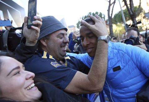 Boca Juniors' Sebastian Villa, right, is hugged by a supporter as the team arrives at their hotel in Madrid Saturday, Dec. 8, 2018. The Copa Libertadores Final between River Plate and Boca Juniors will be played on Dec. 9 in Madrid, Spain, at Real Madrid's stadium. (AP Photo/Andrea Comas)