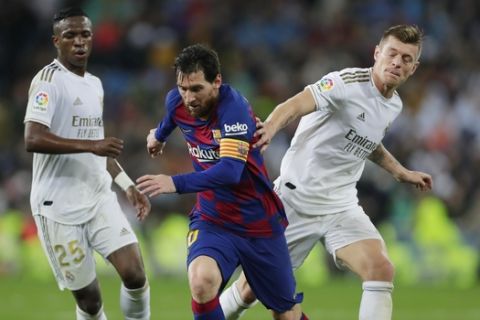 Barcelona's Lionel Messi, center, competes for the ball with Real Madrid's Toni Kroos, right, and Vinicius Junior during the Spanish La Liga soccer match between Real Madrid and Barcelona at the Santiago Bernabeu stadium in Madrid, Spain, Sunday, March 1, 2020. (AP Photo/Manu Fernandez)