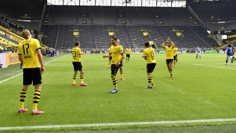 Dortmund's Erling Haaland, left, celebrates after scoring the opening goal during the German Bundesliga soccer match between Borussia Dortmund and Schalke 04 in Dortmund, Germany, Saturday, May 16, 2020. The German Bundesliga becomes the world's first major soccer league to resume after a two-month suspension because of the coronavirus pandemic. (AP Photo/Martin Meissner, Pool)