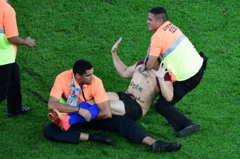 A pitch invader is caught by stewards during the 2014 FIFA World Cup final football match between Germany and Argentina at the Maracana Stadium in Rio de Janeiro on July 13, 2014.  AFP PHOTO / POOL /FRANCOIS XAVIER MARIT