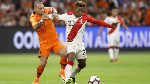 Wesley Sneijder of The Netherlands, left, and Peru's Pedro Aquino vie for the ball during the international friendly soccer match at the Johan Cruijff ArenA in Amsterdam, Netherlands, Thursday, Sept. 6, 2018. The friendly against Peru is the 134th and last for 34-year-old Sneijder, a Dutch record. His first international was a 1-1 draw with Portugal on April 30, 2003. The attacking midfielder has played for clubs including Ajax, Real Madrid and Inter Milan. (AP Photo/Peter Dejong)