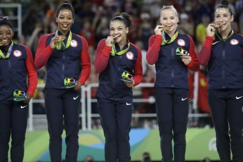 FILE - In this Aug. 9, 2016 file photo, U.S. gymnasts, from left, Simone Biles, Gabrielle Douglas, Lauren Hernandez, Madison Kocian and Aly Raisman hold their gold medals during the medal ceremony for the artistic gymnastics women's team at the 2016 Summer Olympics in Rio de Janeiro, Brazil. MTV said Thursday, Aug. 25, that Biles, Raisman, Douglas, Hernandez and Kocian along with swimmer Michael Phelps, will present awards at Sundays MTV Video Music Awards in New York. (AP Photo/Julio Cortez, File)