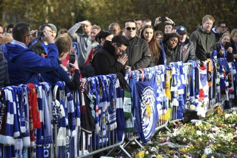 Aiyawatt Srivaddhanaprabha, center, views floral tributes for those who lost their lives in the Leicester City helicopter crash including Leicester City Chairman Vichai Srivaddhanaprabha ahead of the English Premier League soccer match at the King Power Stadium, Leicester, England. Saturday Nov. 10, 2018. (Joe Giddens/PA via AP)