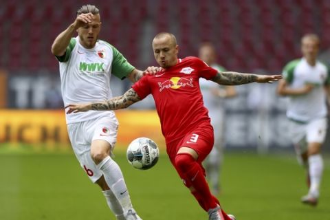 Leipzig's Angelino, right, and Augsburg's Jeffrey Gouweleeuw challenge for the ball during the German Bundesliga soccer match between FC Augsburg and RB Leipzig in Augsburg, Germany, Saturday, June 27, 2020. (AP Photo/Matthias Schrader, Pool)