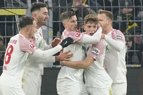 Augsburg's Ermedin Demirovic, center, is hugged by teammates after scoring his side's second goal during the German Bundesliga soccer match between Borussia Dortmund and FC Augsburg in Dortmund, Germany, Sunday, Jan. 22, 2023. (AP Photo/Martin Meissner)
