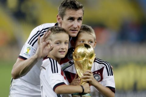 FILE - The July 13, 2014 file photo shows Germany's Miroslav Klose posing with the World Cup trophy and his sons following their 1-0 victory over Argentina after the World Cup final soccer match between Germany and Argentina at the Maracana Stadium in Rio de Janeiro, Brazil.  The German soccer federation says Tuesday Nov. 1, 2016 striker Miroslav Klose, the top scorer in World Cup history, is ending his playing career and will train as a coach.  (AP Photo/Natacha Pisarenko,file)