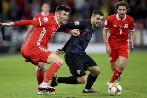 Wales' Kieffer Moore, left, and Croatia's Mateo Kovacic battle for the ball during the Euro 2020 qualifying soccer match at The Cardiff City Stadium, Cardiff, Wales, Sunday Oct. 13, 2019. (Nigel French/PA via AP)