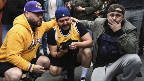Los Angeles Lakers fans Alex Fultz, from left, Eddy Rivas and Rene Alfaro react to the death of former NBA player Kobe Bryant outside of the Staples Center prior to the 62nd annual Grammy Awards on Sunday, Jan. 26, 2020, in Los Angeles. Bryant died Sunday in a helicopter crash near Calabasas, Calif. He was 41. (AP Photo/Chris Pizzello)