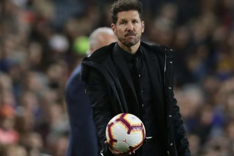 Atletico coach Diego Simeone holds the ball during a Spanish La Liga soccer match between FC Barcelona and Atletico Madrid at the Camp Nou stadium in Barcelona, Spain, Saturday April 6, 2019. (AP Photo/Manu Fernandez)