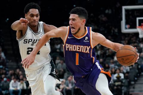 Phoenix Suns guard Devin Booker (1) drives around San Antonio Spurs guard Devin Vassell (24) during the second half of an NBA basketball game, Monday, Jan. 17, 2022, in San Antonio. (AP Photo/Eric Gay)