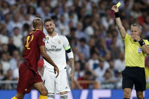 Referee Bjorn Kuipers, right, shows a yellow card to Real defender Sergio Ramos, center, during a Group G Champions League soccer match between Real Madrid and Roma at the Santiago Bernabeu stadium in Madrid, Spain, Wednesday Sept. 19, 2018. (AP Photo/Manu Fernandez)