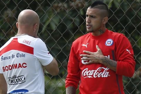 Chile's Arturo Vidal, right, talks with head coach Jorge Sampaoli, center, during a training session at Toca da Raposa 2 center in Belo Horizonte, Brazil, Thursday, June 19, 2014.  Chile plays in group B of the 2014 soccer World Cup. (AP Photo/Victor R. Caivano)
