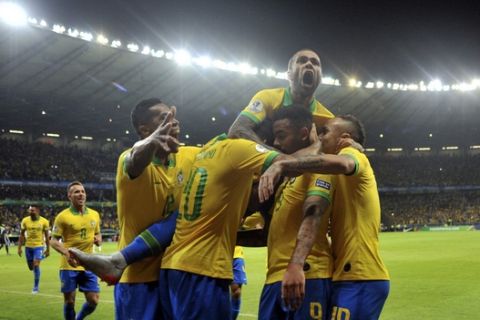 Brazil's Dani Alves, top, jumps on top of his teammates after teammate Gabriel Jesus scored their team's first goal against Argentina during a Copa America semifinal soccer match at Mineirao stadium in Belo Horizonte, Brazil, Tuesday, July 2, 2019. (AP Photo/Eugenio Savio)