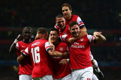 LONDON, ENGLAND - OCTOBER 01:  Mesut Oezil (C)of Arsenal is congratulated by teammates after scoring the opening goal during UEFA Champions League Group F match between Arsenal FC and SSC Napoli at Emirates Stadium on October 1, 2013 in London, England.  (Photo by Paul Gilham/Getty Images)