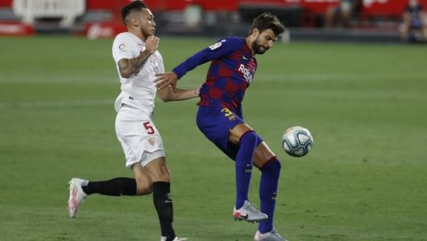 CORRECTING NAMES OF BOTH PLAYERS : FC Barcelonas Gerard Pique, right, and Sevillas Lucas Ocampos in action during the Spanish La Liga soccer match between Sevilla and FC Barcelona at the Ramon Sanchez-Pizjuan stadium in Seville, Spain, Friday, June 19, 2020. (AP Photo/Angel Fernandez)
