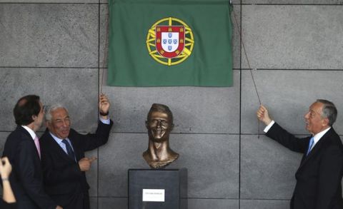 Portuguese Prime Minister Antonio Costa, 2nd left and Portuguese president Marcelo Rebelo de Sousa, right, unveil a bust of Real Madrid's Cristiano Ronaldo at the Madeira international airport outside Funchal, the capital of Madeira island, Portugal, Wednesday March 29, 2017. Madeira International Airport has been renamed after local soccer star Cristiano Ronaldo on Wednesday during a ceremony, with family, at the airport outside his Funchal hometown. (AP Photo/Armando Franca)