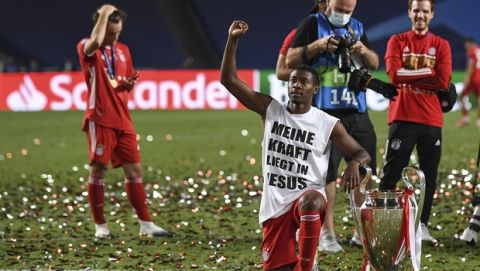 Bayern's David Alaba knees with a shirt reading "My strength lies in Jesus" beside the trophy on the pitch after the Champions League final soccer match between Paris Saint-Germain and Bayern Munich at the Luz stadium in Lisbon, Portugal, Sunday, Aug. 23, 2020. (David Ramos/Pool via AP)