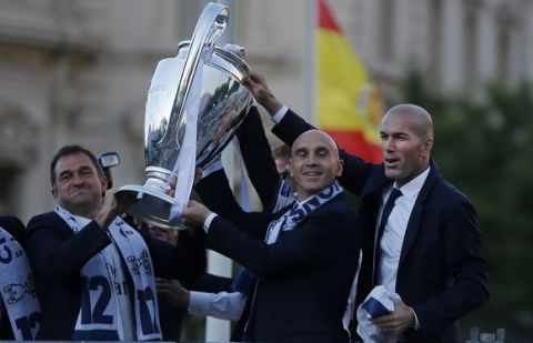 Real Madrid's head coach Zinedine Zidane, right holds the trophy with club officials during celebrations in Cibeles square after winning the Champions League final, Madrid, Spain, Sunday June 4, 2017. Real Madrid became the first team in the Champions League era to win back-to-back titles with their 4-1 victory over Juventus in Cardiff Saturday. (AP Photo/Paul White)
