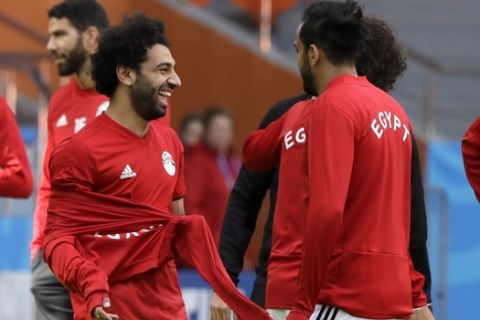 Egypt's Mohamed Salah, left, jokes with teammates during Egypt's official training on the eve of the group A match between Egypt and Uruguay at the 2018 soccer World Cup in the Yekaterinburg Arena, Yekaterinburg, Russia, Thursday, June 14, 2018. (AP Photo/Mark Baker)