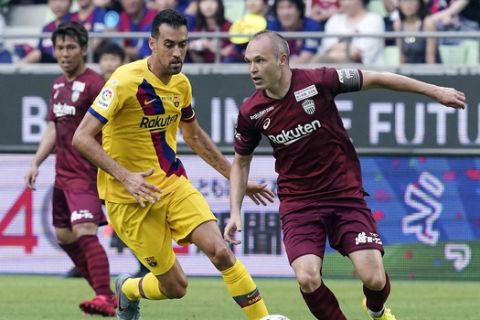 FC Barcelona's Sergio Busquets, left, and Vissel Kobe's Andres Iniesta, right compete for the ball during a friendly soccer match between FC Barcelona and Vissel Kobe at Noevir Stadium in Kobe, western Japan Saturday, July 27, 2019. between FC Barcelona won 2-0. (AP Photo/Eugene Hoshiko)