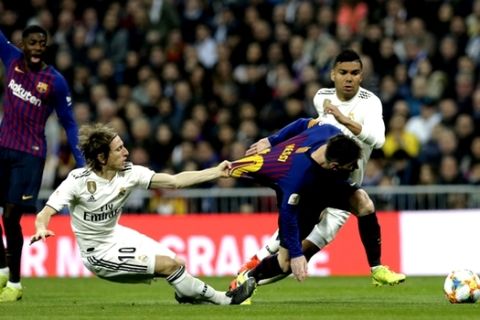 Barcelona forward Lionel Messi, right, is tackled by Real midfielder Luka Modric during the Copa del Rey semifinal second leg soccer match between Real Madrid and FC Barcelona at the Bernabeu stadium in Madrid, Spain, Wednesday Feb. 27, 2019. (AP Photo/Andrea Comas)
