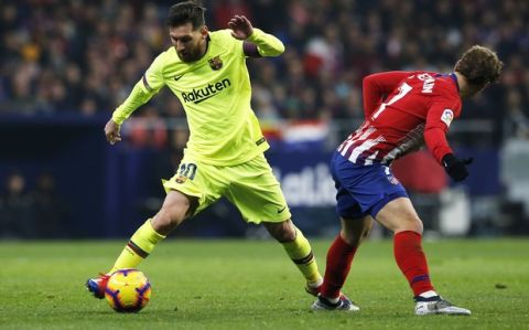 Barcelona's Lionel Messi drives the ball past Atletico's Antoine Griezmann, right, during a Spanish La Liga soccer match between Atletico Madrid and FC Barcelona at the Metropolitano stadium in Madrid, Saturday, Nov. 24, 2018. (AP Photo/Paul White)
