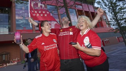 Liverpool supporters celebrates outside Anfield Stadium in Liverpool, England, Thursday, June 25, 2020 after hearing Chelsea had scored in the English Premier League soccer match between Chelsea and Manchester City. Liverpool will be crowned Premier League champions if Manchester City fail to beat Chelsea. (AP Photo/Jon Super)