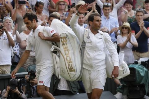 Switzerland's Roger Federer, left, leaves the court after beating Spain's Rafael Nadal, right, in a Men's singles semifinal match on day eleven of the Wimbledon Tennis Championships in London, Friday, July 12, 2019. (AP Photo/Kirsty Wigglesworth)