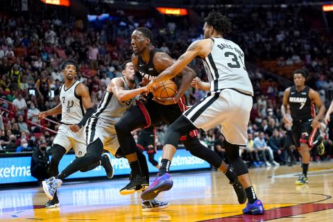 Miami Heat center Bam Adebayo, center, drives to the basket as San Antonio Spurs guard Tre Jones, left, and forward Keita Bates-Diop (31) defend during the second half of an NBA basketball game, Saturday, Feb. 26, 2022, in Miami. The Heat won 133-129. (AP Photo/Lynne Sladky)