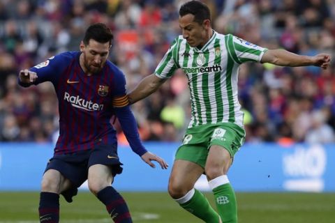 FC Barcelona's Lionel Messi, left, duels for the ball against Betis' Andres Guardado during the Spanish La Liga soccer match between FC Barcelona and Betis at the Camp Nou stadium in Barcelona, Spain, Sunday, Nov. 11, 2018. (AP Photo/Manu Fernandez)