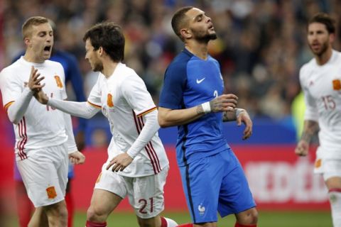 France's Layvin Kurzawa, 2nd right, reacts as Spain's scorer David Silva, 2nd left, and his teammate Gerard Deulofeu, left, celebrate the opening goal during the international friendly soccer match between France and Spain at the Stade de France in Paris, France, Tuesday, March 28, 2017. (AP Photo/Christophe Ena)