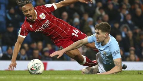 Manchester City's John Stones, right, challenges for the ball with with Bristol City's Bobby Reid during the English League Cup semifinal first leg soccer match between Manchester City and Bristol City at the Etihad stadium in Manchester, England, Tuesday, Jan. 9, 2018. (AP Photo/Dave Thompson)