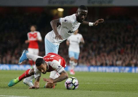 Arsenal's Theo Walcott, bottom and West Ham's Arthur Masuaku challenge for the ball during the English Premier League soccer match between Arsenal and West Ham at the Emirates stadium in London, Wednesday, April 5, 2017.(AP Photo/Frank Augstein)