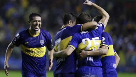 FILE - In this May 11, 2014 file photo, Boca Juniors' Juan Roman Riquelme, left, approaches his teammates to congratulate Claudio Riano, center, after he scored a goal against Lanus during an Argentine league soccer match in Buenos Aires, Argentina. Boca won 3-1. (AP Photo/Natacha Pisarenko, File)