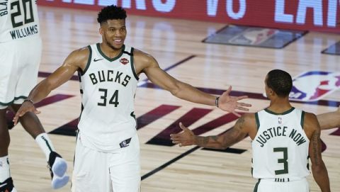 Milwaukee Bucks forward Giannis Antetokounmpo (34) celebrates the team's win over the Orlando Magic with guard George Hill (3) and center Robin Lopez (42) in an NBA basketball first round playoff game, Thursday, Aug. 20, 2020, in Lake Buena Vista, Fla. (AP Photo/Ashley Landis, Pool)