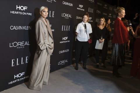 Lady Gaga, left, arrives on the carpet at the 25th Annual ELLE Women in Hollywood Celebration, Monday, Oct. 15, 2018, in Los Angeles. At far right being interviewed is actress Charlize Theron. (Photo by Chris Pizzello/Invision/AP)